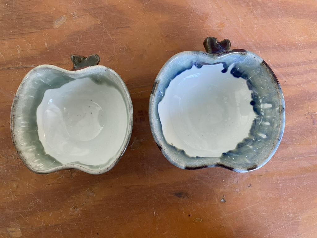 Two apple-shaped stoneware bowls with a drippy red-green glaze